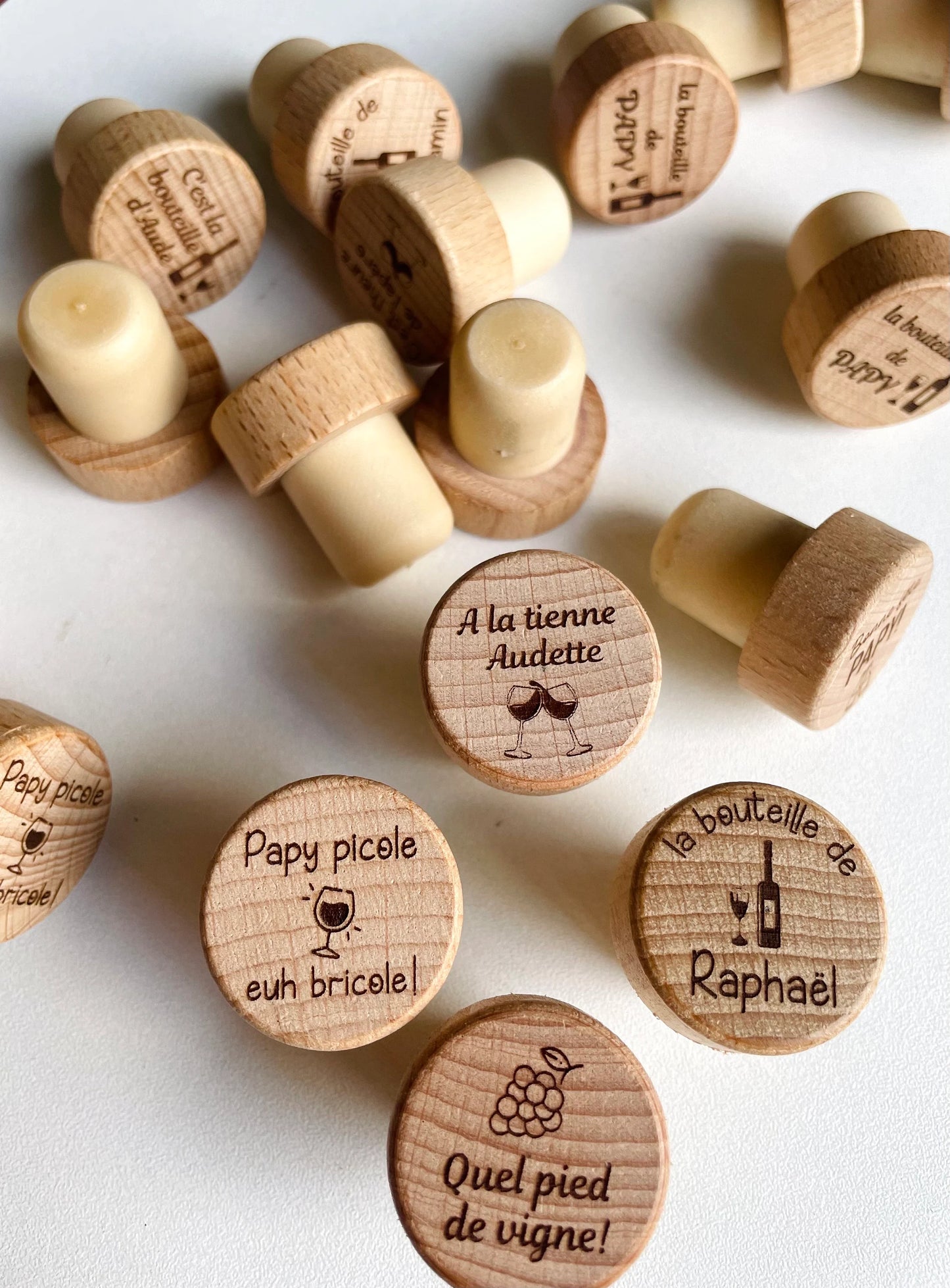 Collection de bouchons en bois gravés avec différents logos, textes et designs personnalisés.