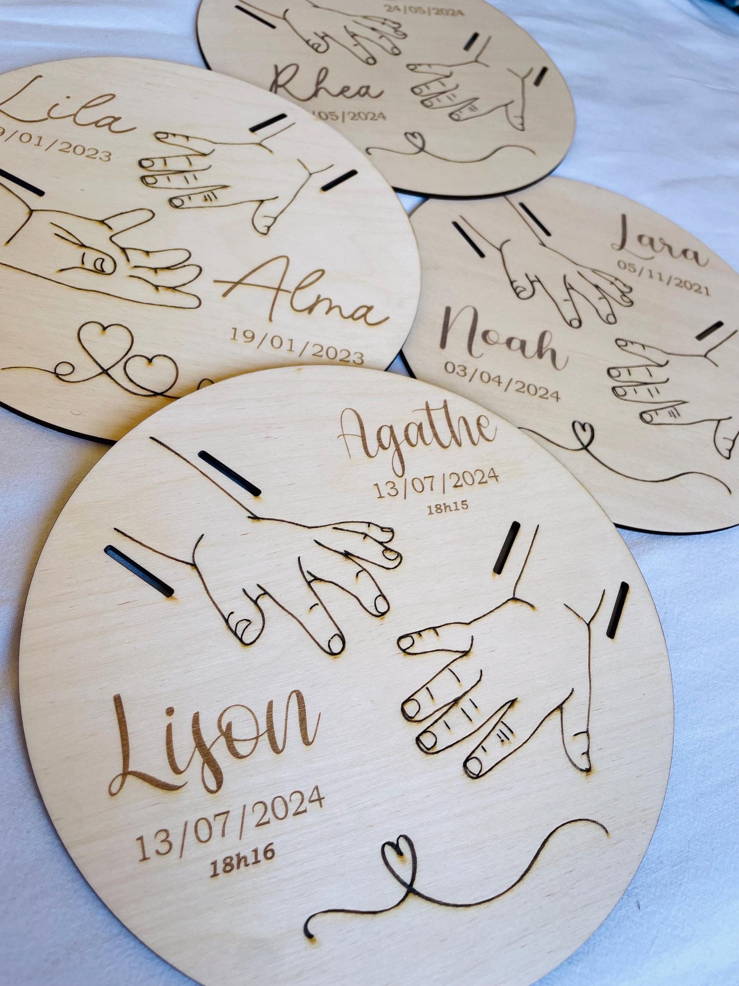 Collection de plaques de naissance personnalisées en bois avec différents prénoms, dates et modèles gravés.